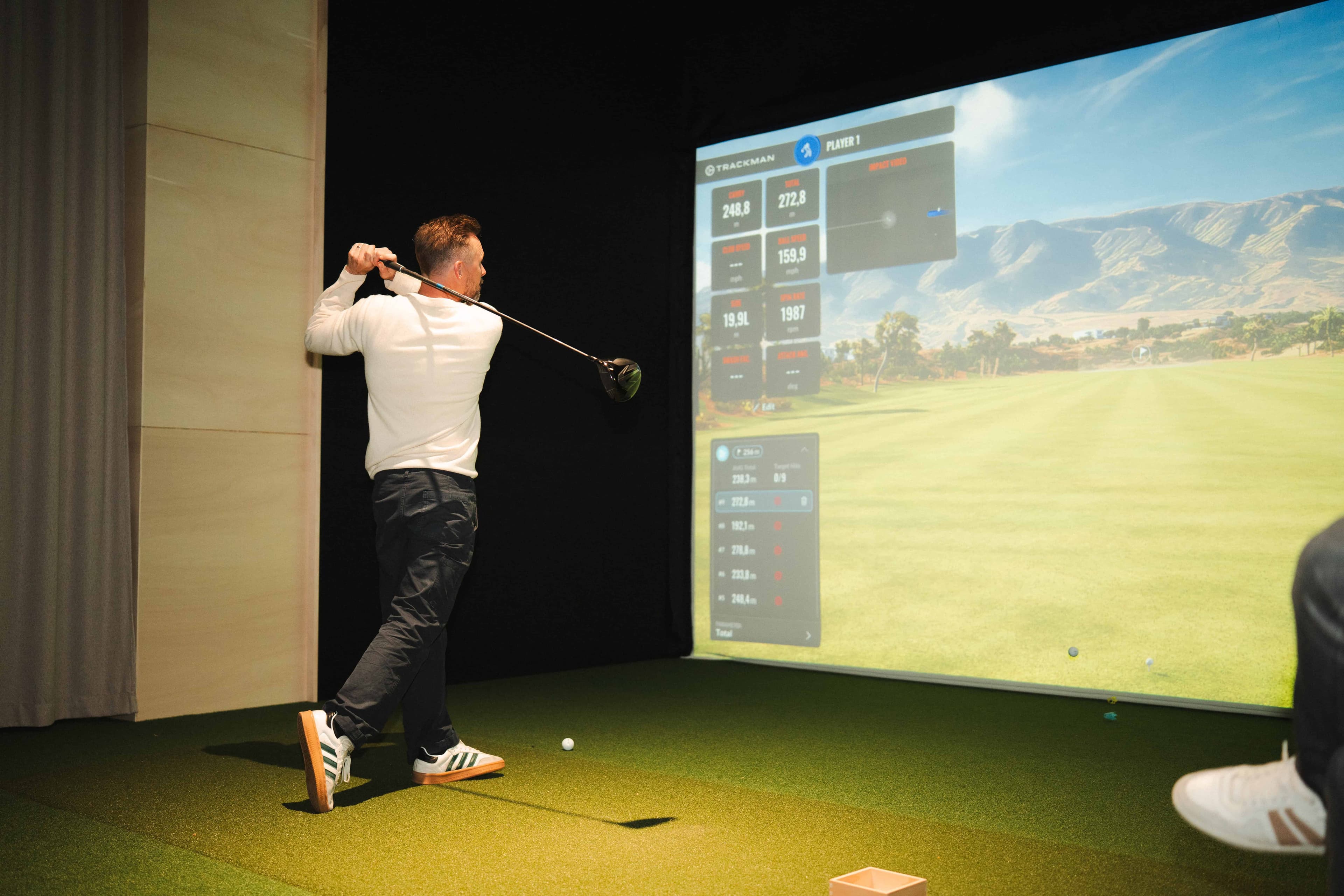 En spelare som slår ut på veckans bana i en TrackMan-simulator hos USE